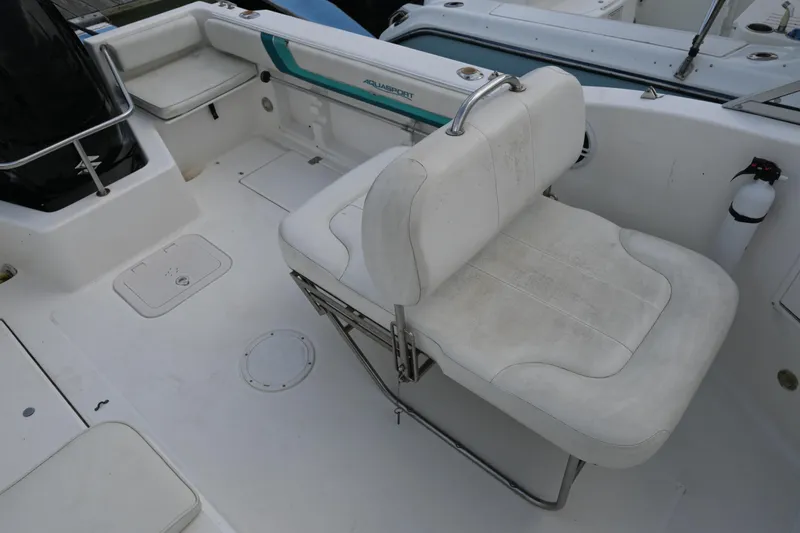 Slide: The Image of 1999 Aquasport 215 Dual Console boat interior with white seating and storage compartments. - 10