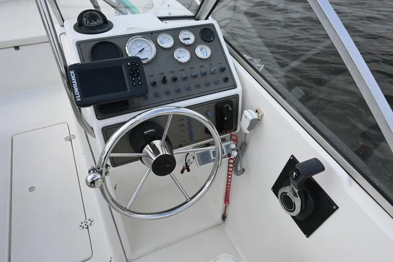 Slide: The Image of 1999 Aquasport 215 Dual Console boat dashboard with steering wheel and navigation instruments. - 12