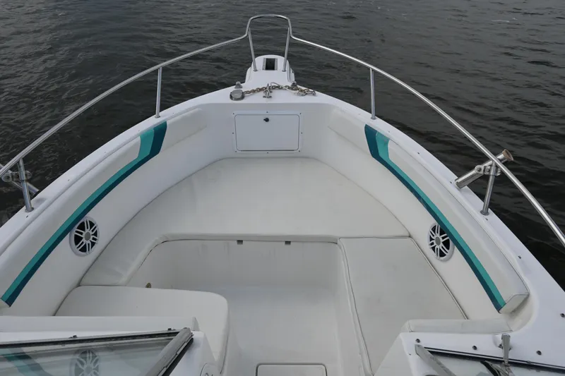 Slide: The Image of 1999 Aquasport 215 Dual Console boat interior with white seating and teal accents on water. - 14