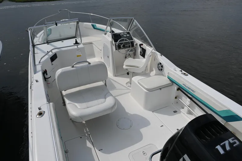 Slide: The Image of 1999 Aquasport 215 Dual Console boat with white seating and steering, on calm water. - 6