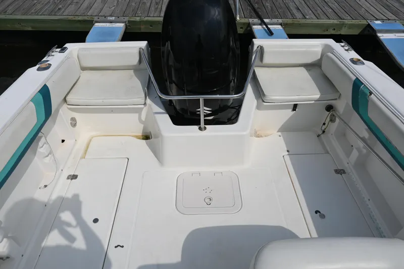 Slide: The Image of 1999 Aquasport 215 Dual Console boat interior with seating and motor, docked at a wooden pier. - 7