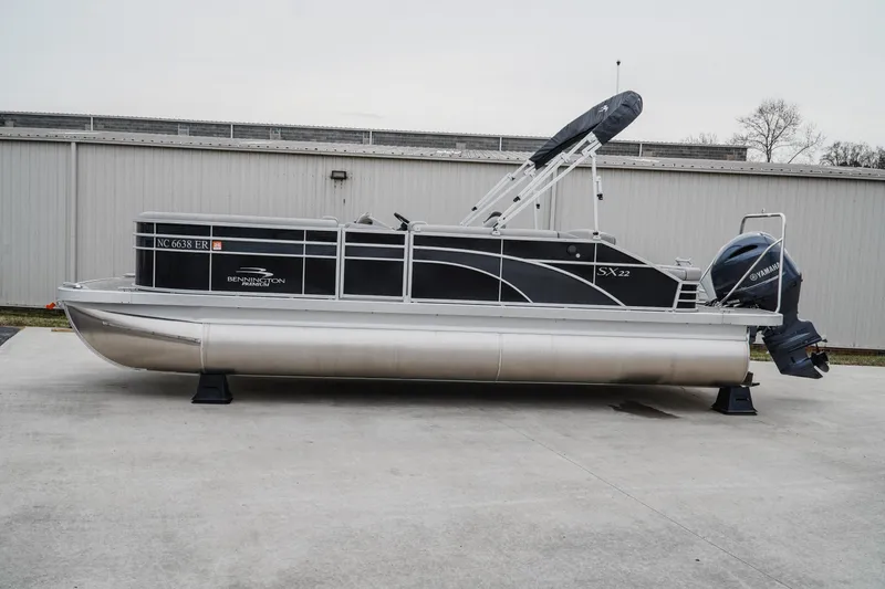 The Image of 2021 Bennington 22SSBXP pontoon boat with Yamaha outboard motor, parked on concrete. - 2
