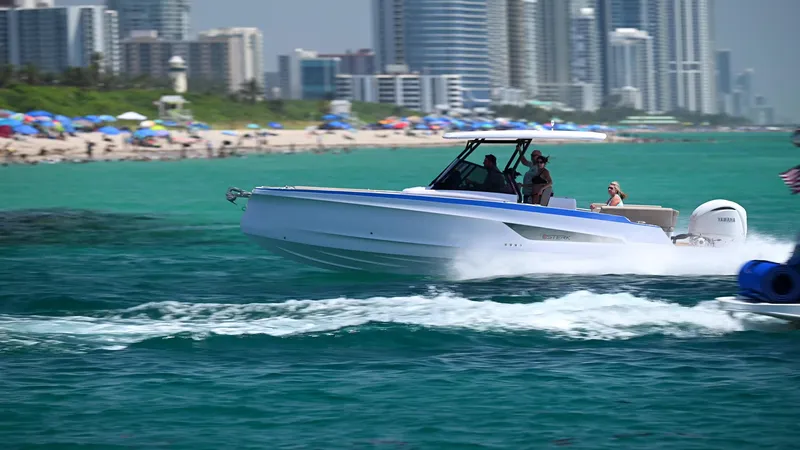 Slide: The Image of 2026 STERK 31 WB Super Sport boat cruising near a city beach with skyscrapers. - 2