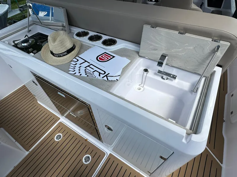 Slide: The Image of Outdoor kitchenette on 2026 STERK 31 WB Super Sport boat with sink, stove, and accessories. - 7
