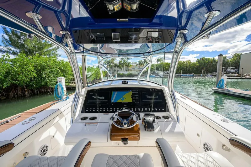 Slide: The Image of 2025 Valhalla Boatworks V-41 helm with advanced navigation system, docked by lush greenery. - 3