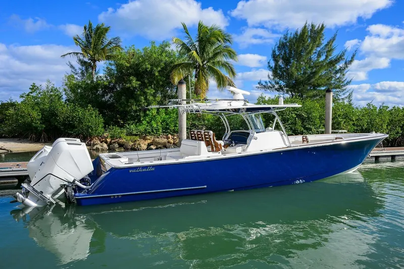 Slide: The Image of 2025 Valhalla Boatworks V-41 in blue, docked near tropical trees under a clear sky. - 56