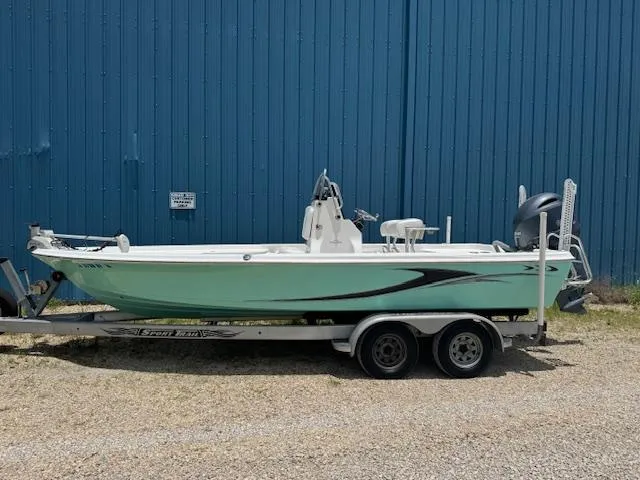 Slide: The Image of 2016 Blue Wave 2200 PureBay boat on trailer, parked by a blue wall. - 2