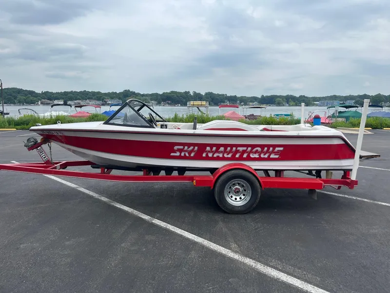 Slide: The Image of 1993 Correct Craft Ski Nautique boat on trailer by a lakeside parking lot. - 1