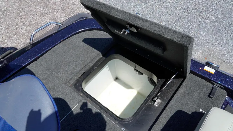 Slide: The Image of 2021 Skeeter ZX200 boat with open storage compartment, gray carpet, and blue seat. - 12