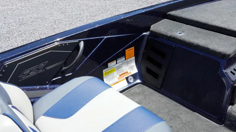 Slide: The Image of 2021 Skeeter ZX200 boat interior with blue and gray seating, carpeted flooring, and storage compartments. - 26