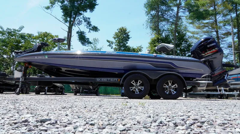 Slide: The Image of 2021 Skeeter ZX200 boat on trailer, parked on gravel, surrounded by trees. - 32