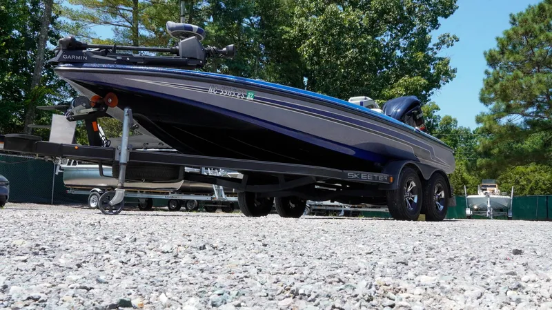 Slide: The Image of 2021 Skeeter ZX200 boat on trailer, parked on gravel, surrounded by trees. - 34