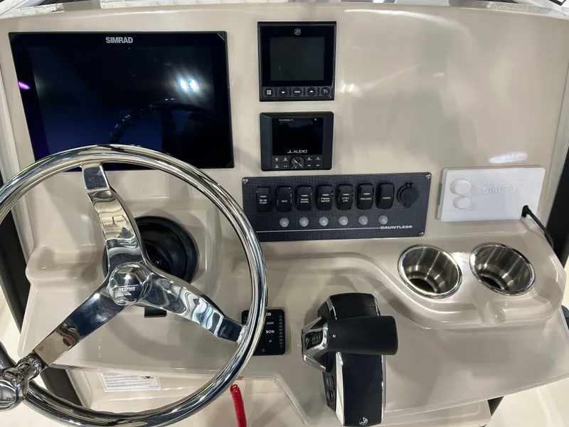 Slide: The Image of 2025 Boston Whaler 220 Dauntless dashboard with steering wheel, controls, and Simrad display. - 16