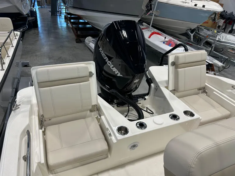 Slide: The Image of 2025 Boston Whaler 220 Dauntless boat interior with Mercury engine, white seating, and cup holders. - 6