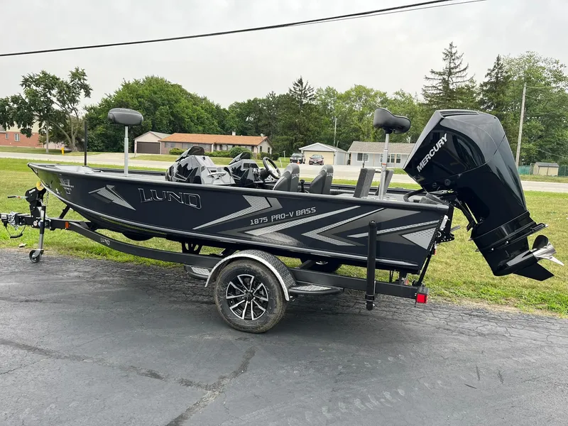Slide: The Image of 2026 Lund 1875 Pro-V Bass XS boat on trailer, featuring sleek design and Mercury outboard motor. - 2