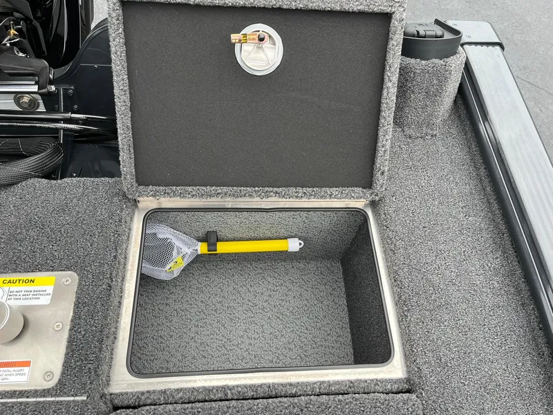 Slide: The Image of Open storage compartment in 2026 Lund 1875 Pro-V Bass XS boat with a yellow-handled net. - 21