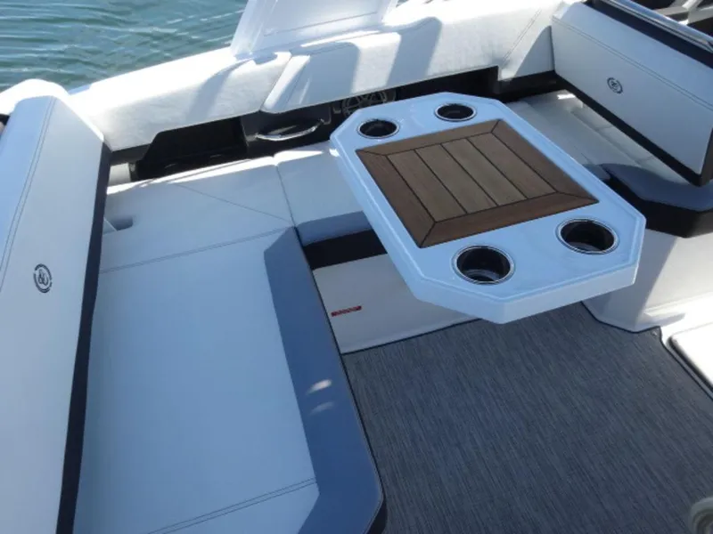 Slide: The Image of 2024 Cobalt R6 boat interior with seating and a wooden table featuring cup holders. - 15