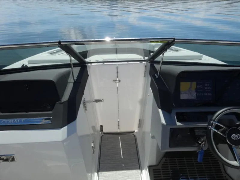 Slide: The Image of 2024 Cobalt R6 boat cockpit with steering wheel and dashboard on calm water. - 23