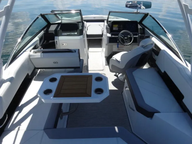 Slide: The Image of 2024 Cobalt R6 boat interior with seating, table, and steering wheel on calm water. - 7