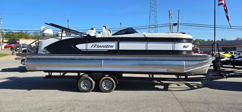 Slide: The Image of 2025 Manitou 25 LX SRW pontoon boat on trailer, parked outdoors. - 1
