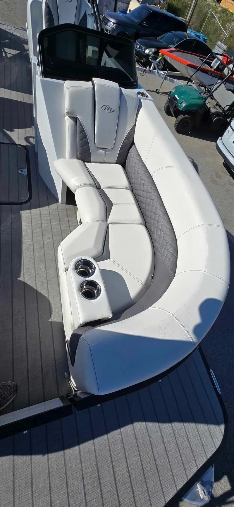 Slide: The Image of 2025 Manitou 25 LX SRW boat with luxurious white seating and cup holders. - 11