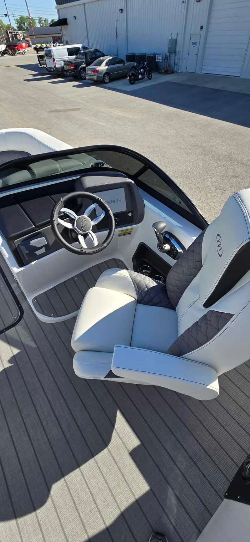 Slide: The Image of 2025 Manitou 25 LX SRW boat cockpit with steering wheel and captain's chair. - 16
