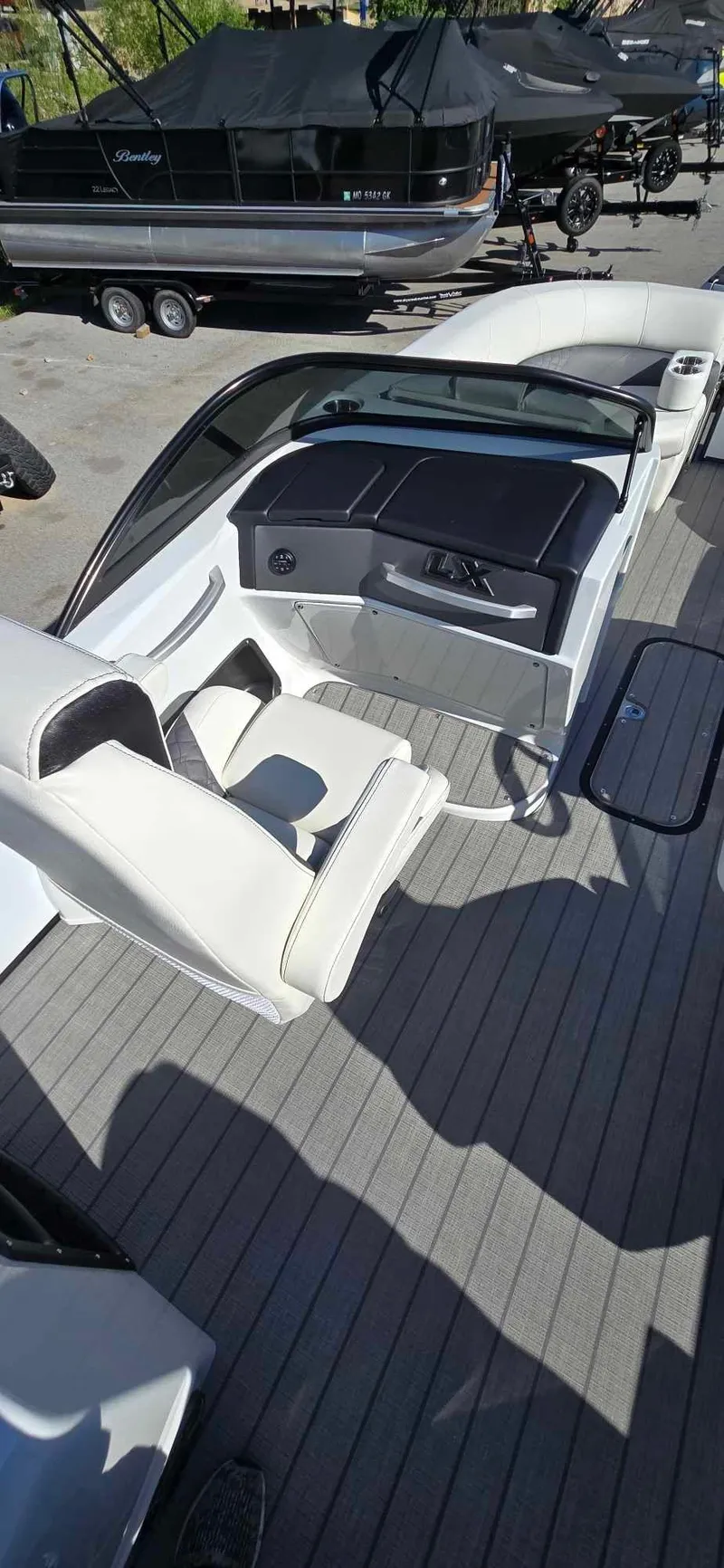 Slide: The Image of 2025 Manitou 25 LX SRW boat interior with white seating and sleek dashboard design. - 17