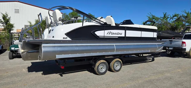 Slide: The Image of 2025 Manitou 25 LX SRW pontoon boat on trailer, parked outdoors. - 6