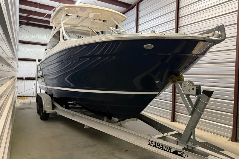 Slide: The Image of 2020 Cutwater C-24 DC boat on trailer, parked outdoors under clear blue sky. - 1
