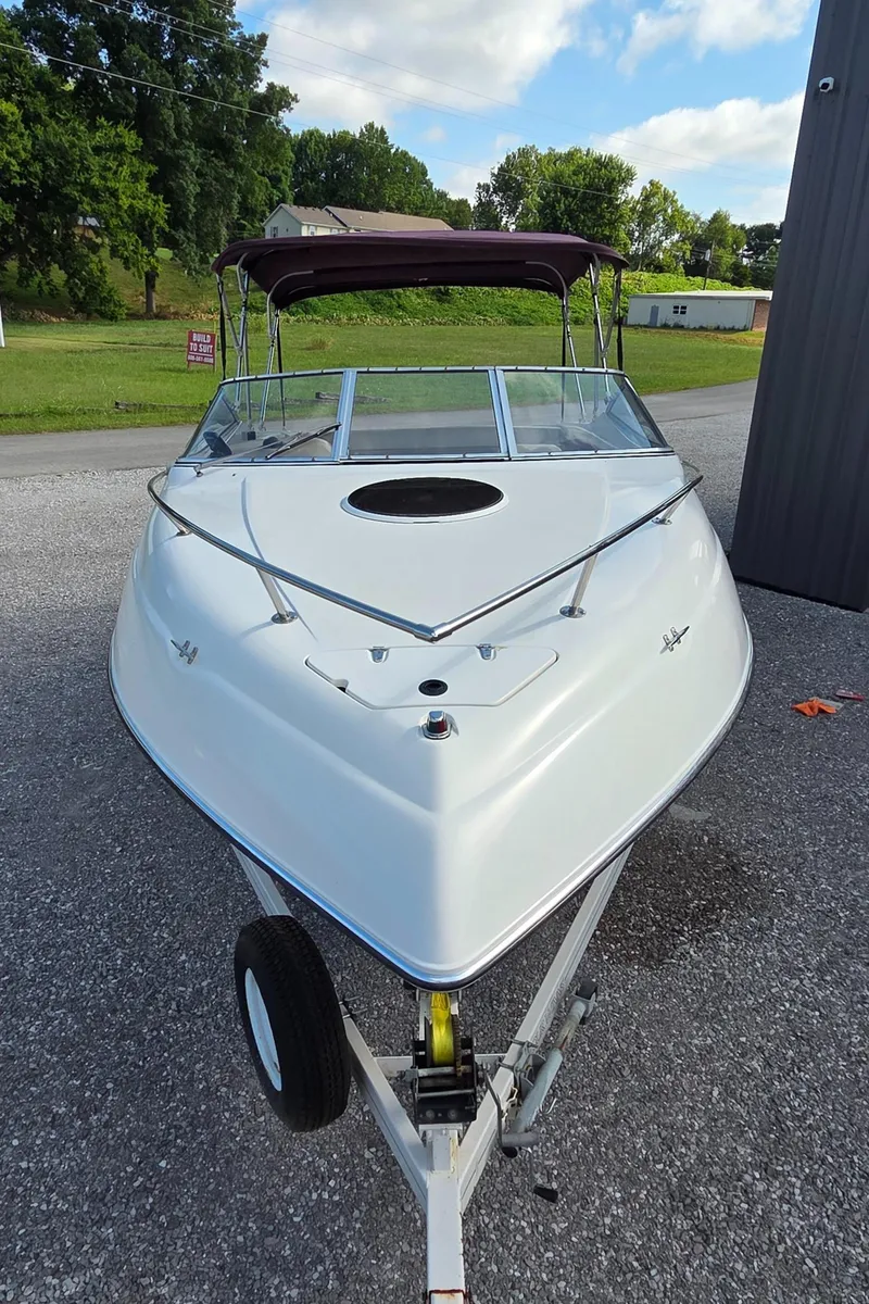 Slide: The Image of 1995 Four Winns 245 Sundowner boat on trailer, parked outdoors, with trees in the background. - 3