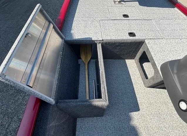 Slide: The Image of 2024 Tracker Pro 170 boat storage compartment with paddle, open lid, and gray interior. - 11