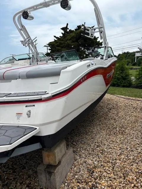Slide: The Image of 2019 MasterCraft NXT22 boat on gravel, featuring sleek design and red accents. - 11