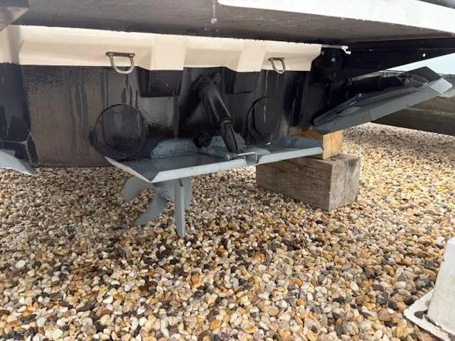 Slide: The Image of 2019 MasterCraft NXT22 boat underside with propeller and rudder on gravel surface. - 14