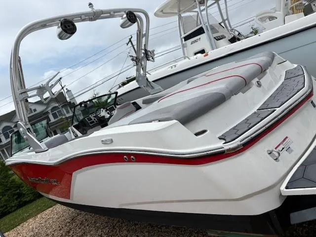Slide: The Image of 2019 MasterCraft NXT22 boat with red accents and wakeboard tower, parked on gravel. - 8