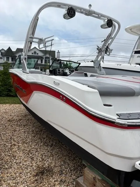 Slide: The Image of 2019 MasterCraft NXT22 boat with red and white design, parked on gravel. - 9