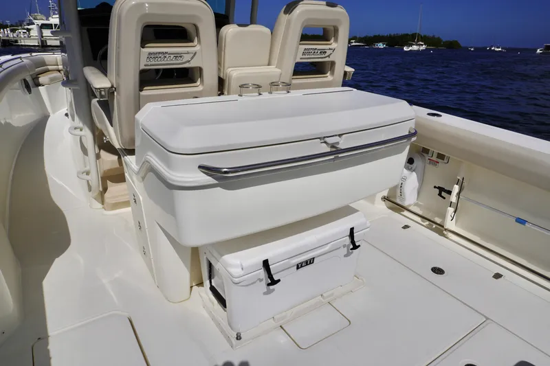 Slide: The Image of 2021 Boston Whaler 330 Outrage interior with seating and storage, docked by the water. - 17