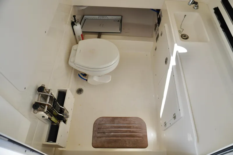 Slide: The Image of 2021 Boston Whaler 330 Outrage boat bathroom with toilet, sink, and storage. - 19