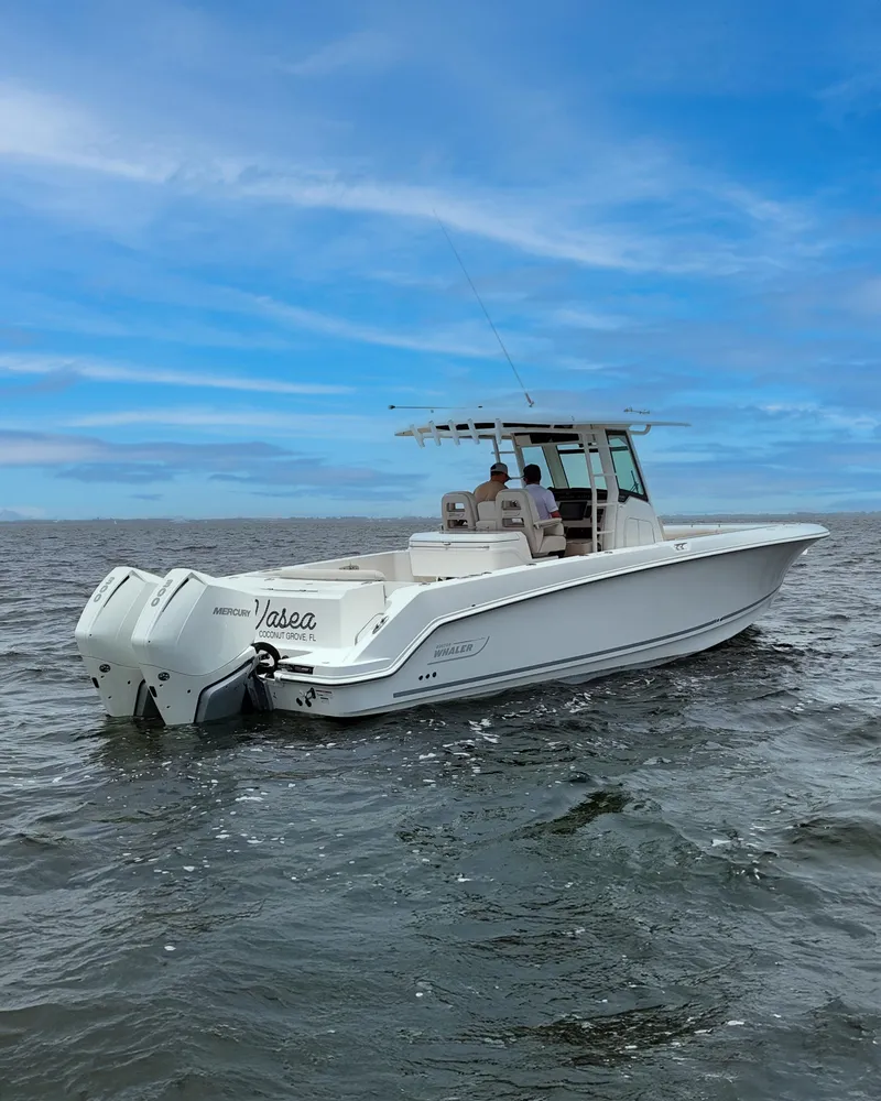 Slide: The Image of 2021 Boston Whaler 330 Outrage boat on open water under a clear blue sky. - 2
