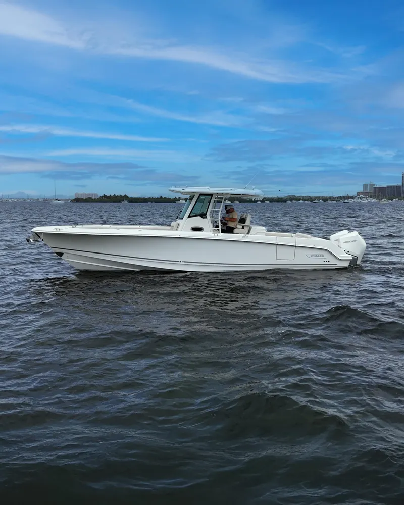 Slide: The Image of 2021 Boston Whaler 330 Outrage boat on open water under a clear blue sky. - 6