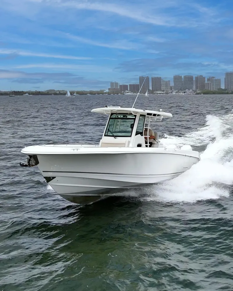 Slide: The Image of 2021 Boston Whaler 330 Outrage cruising on water with city skyline in background. - 7