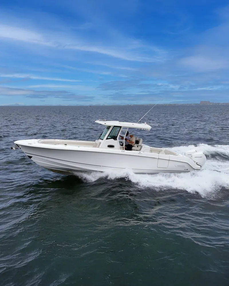 Slide: The Image of 2021 Boston Whaler 330 Outrage cruising on open water under a clear blue sky. - 9
