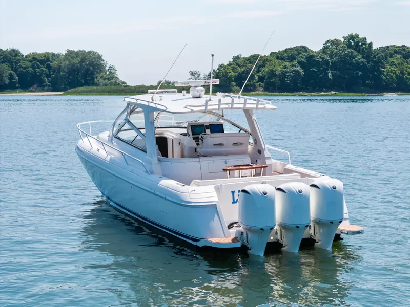 Slide: The Image of 2015 Intrepid 430 Sport Yacht on serene water with lush green shoreline. - 4