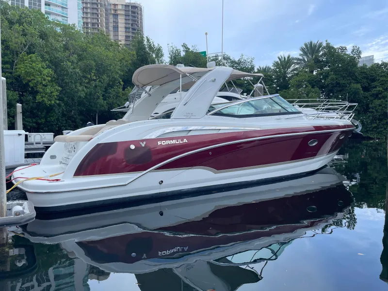 The Image of 2010 Formula 350ss boat docked, featuring sleek design and maroon accents, surrounded by greenery. - 0