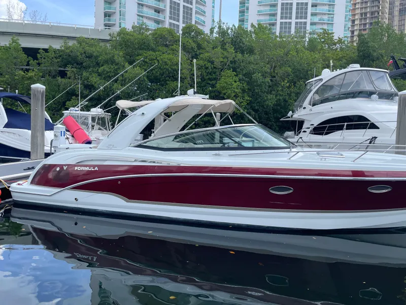 Slide: The Image of 2010 Formula 350ss boat docked, featuring sleek design and maroon accents, with cityscape background. - 1