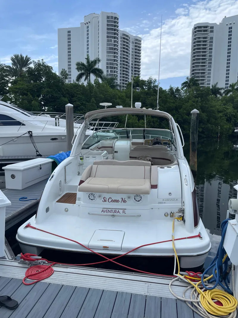 Slide: The Image of 2010 Formula 350ss boat docked, with high-rise buildings and lush greenery in the background. - 2