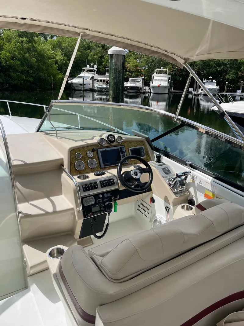 Slide: The Image of 2010 Formula 350ss boat cockpit with steering wheel, control panel, and seating, docked near other boats. - 5