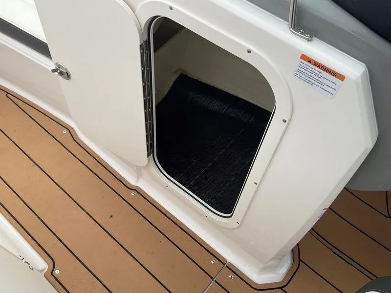 Slide: The Image of 2023 Chaparral 23 SSi boat storage compartment with open door on teak-style deck. - 33