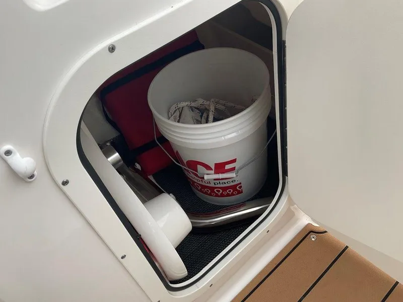 Slide: The Image of Storage compartment in a 2023 Chaparral 23 SSi boat with a bucket and equipment. - 39