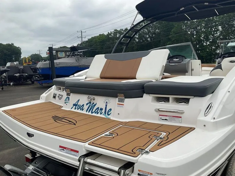 Slide: The Image of 2023 Chaparral 23 SSi boat with cushioned seating and teak-style deck, docked outdoors. - 9