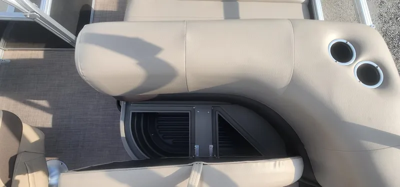 Slide: The Image of 2024 Sun Tracker Party Barge 18 DLX interior with beige seating and cup holders. - 16